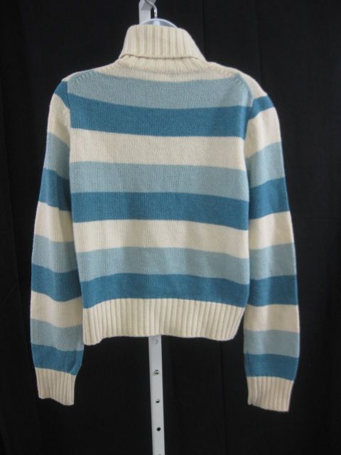   sweater has a blue and cream stripe design, a ribbed turtleneck, and